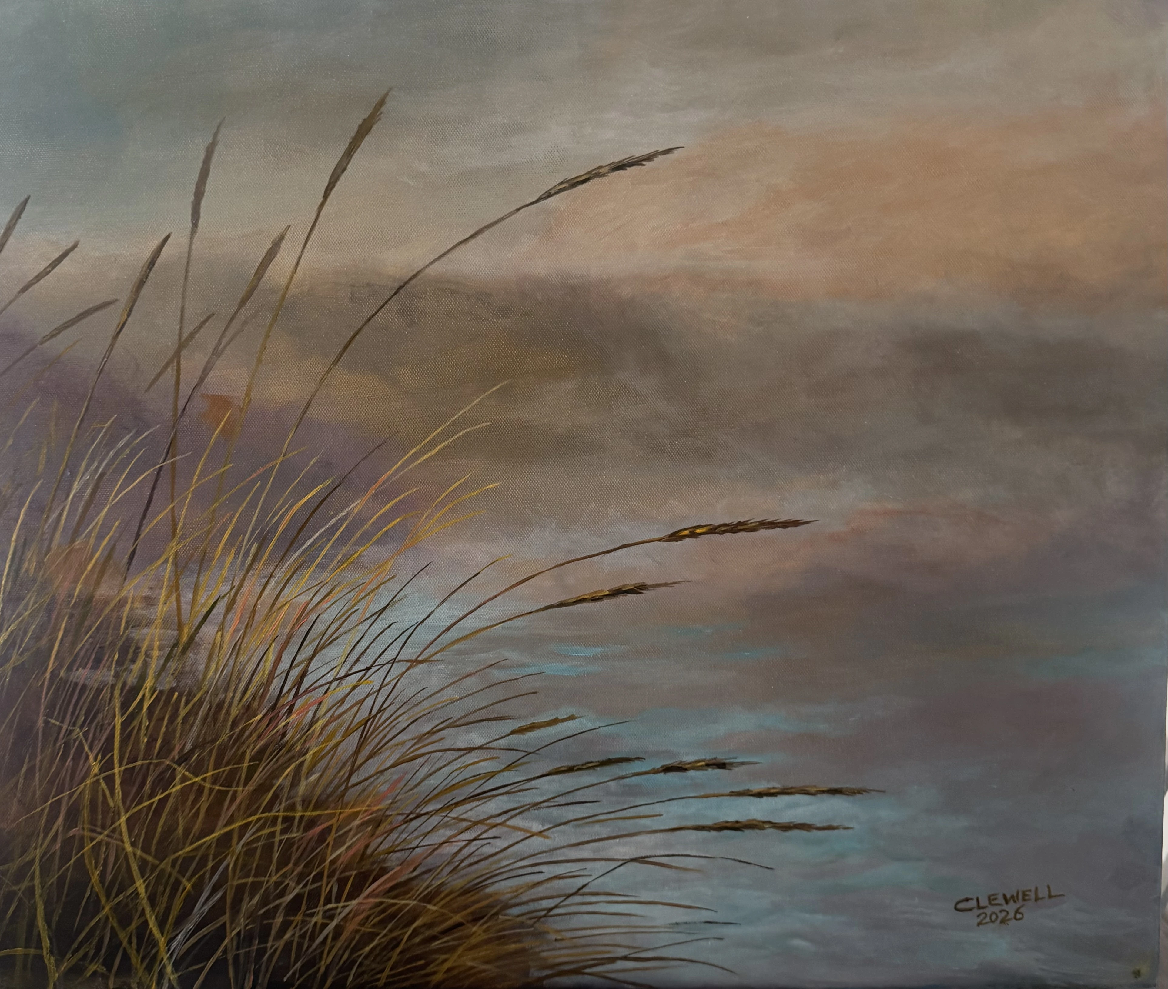 Tall coastal grasses bending beside calm water under a soft dusk sky