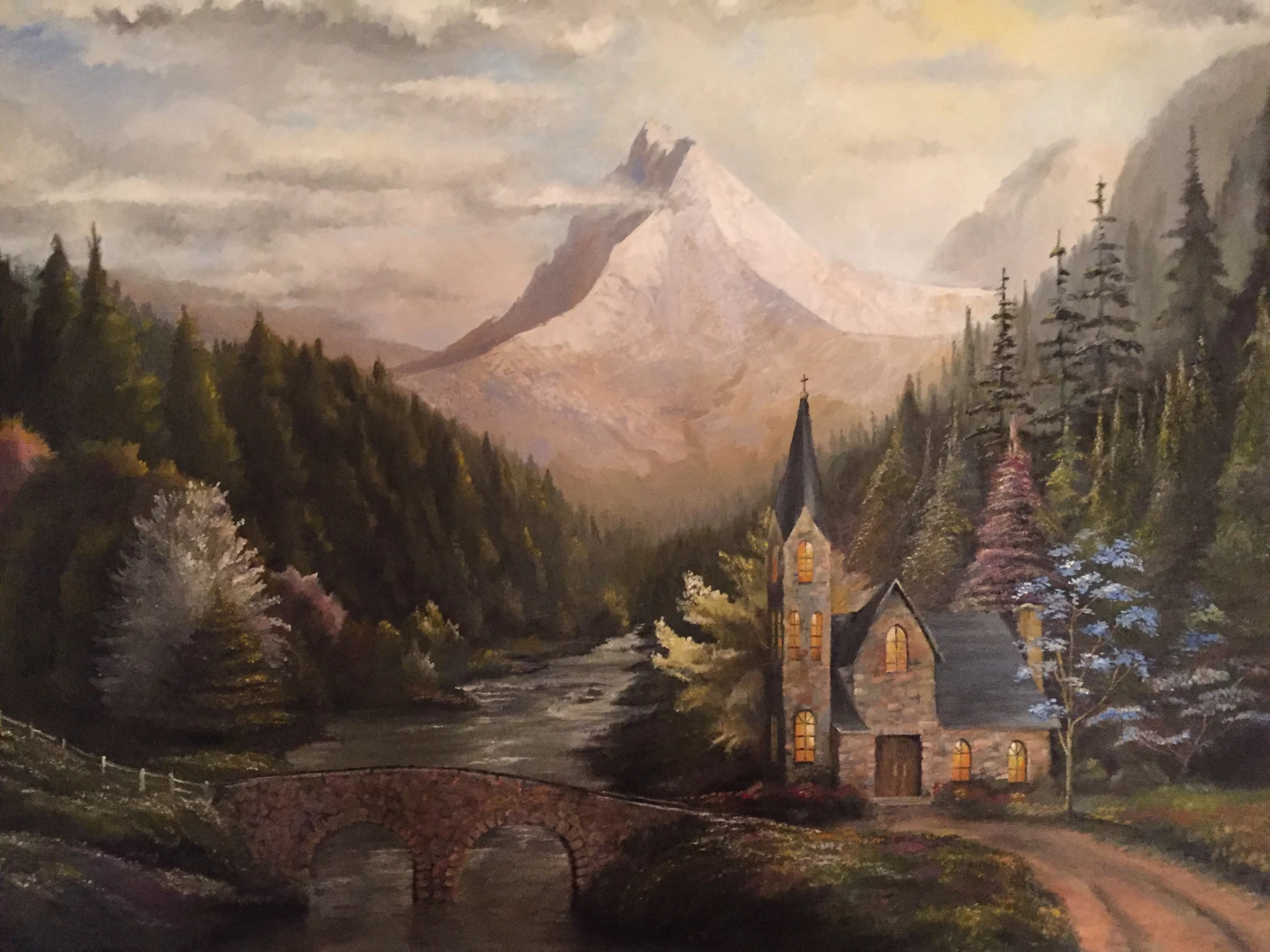 Oil painting of a mountain landscape with a stone chapel, stone bridge, evergreen forest, and snow capped peak